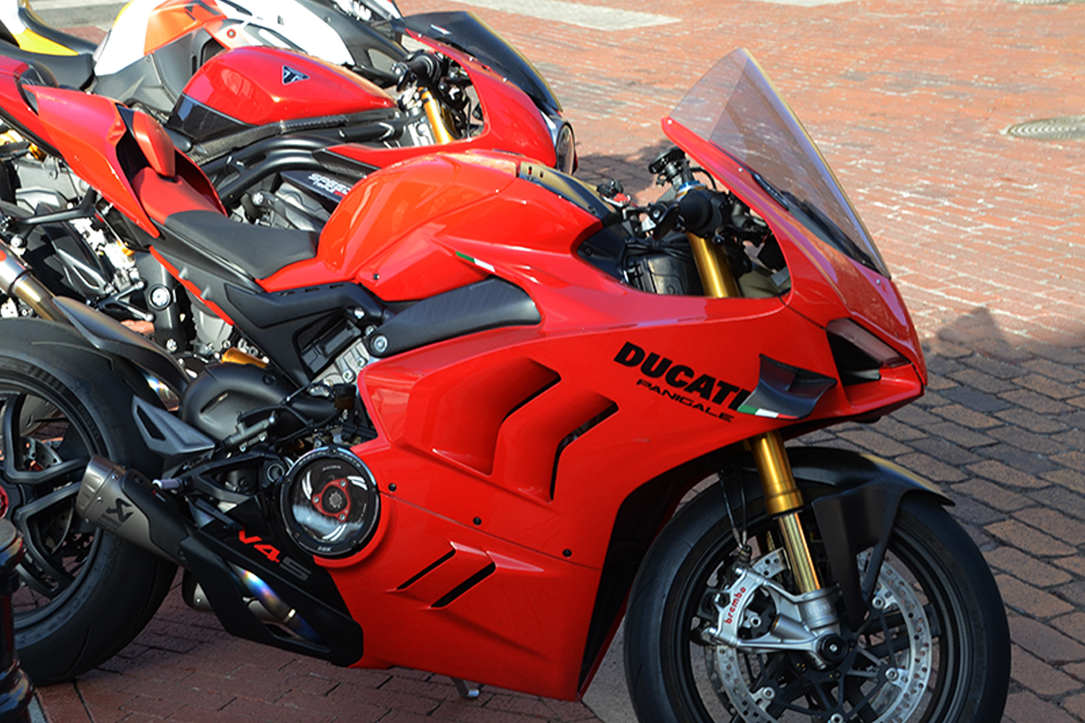 Red Ducati motorcycle parked on brick pavement.